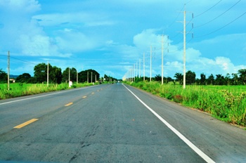 The highway stretches away into green fields and azure skies